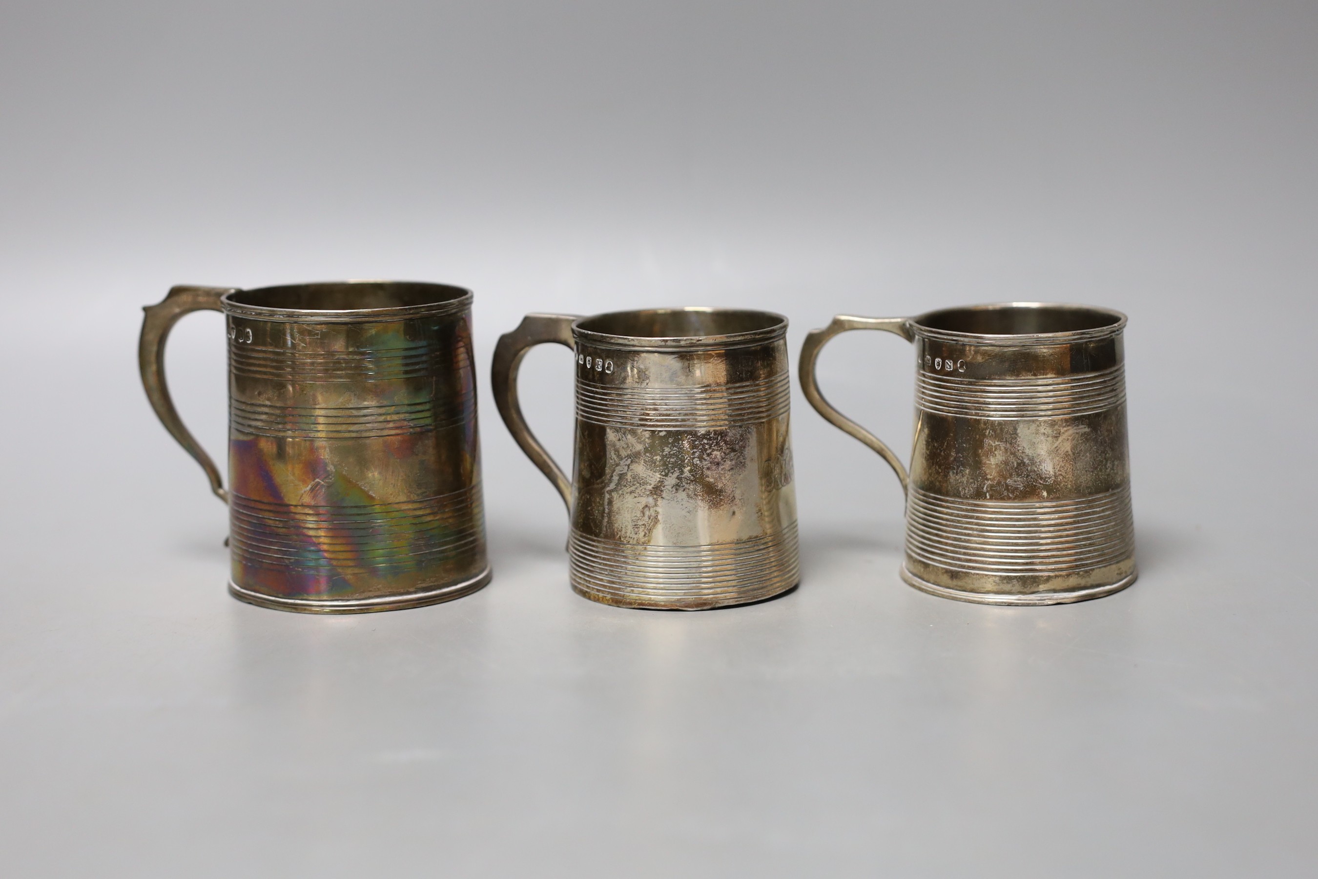 Three small Georgian silver mugs, two with two reeded bands, Stephen Adams I, London, 1801, 64mm and makers mark rubbed, London, 1808 (with later engraved inscription to the base) and one with three reeded bands, London,